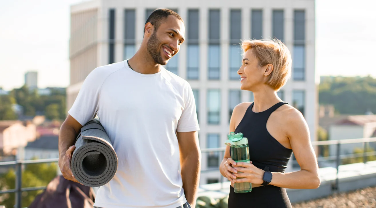 A man and woman in workout attire chatting on a rooftop, illustrating ways to make friends in your 30s and 40s.